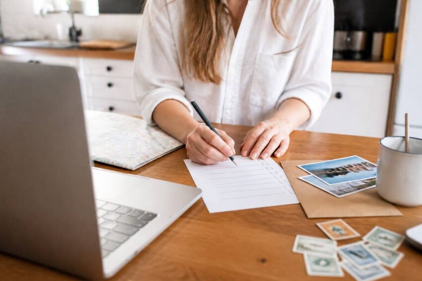 Checklist voor het vergelijken van vakanties aan een keukentafel met laptop en papieren notities