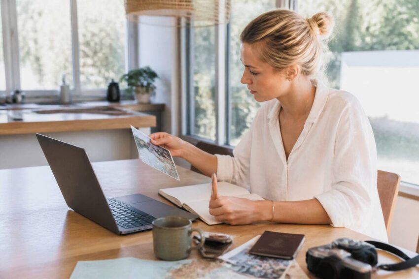 Iemand die vakantie-opties vergelijkt op een laptop met notities op tafel